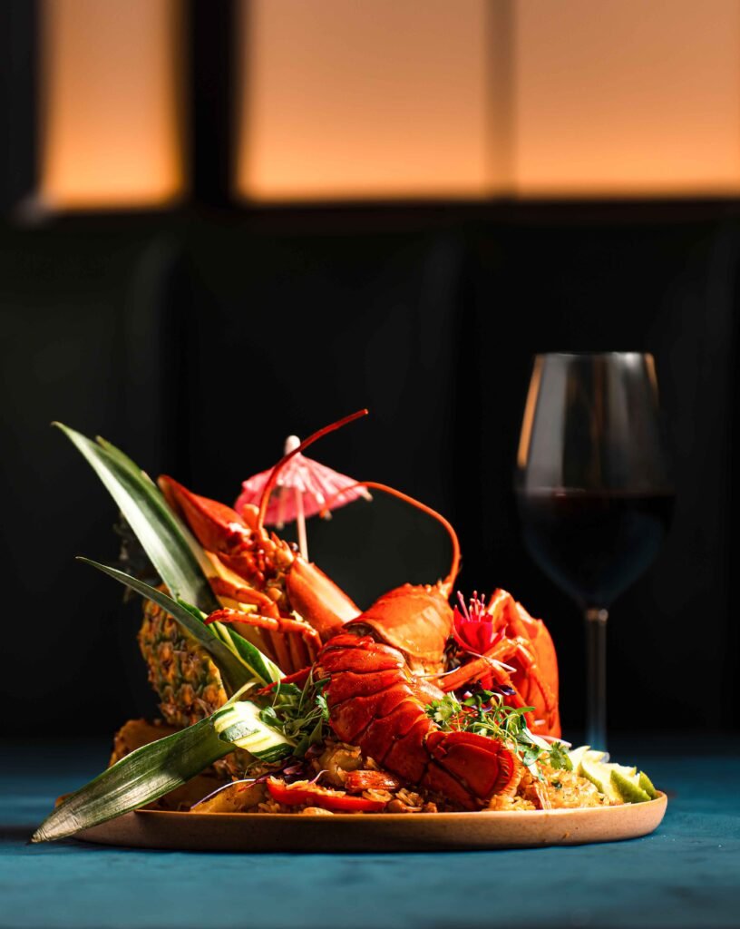Delicious lobster dish served with fresh greens and a glass of red wine. Perfect for fine dining and.
